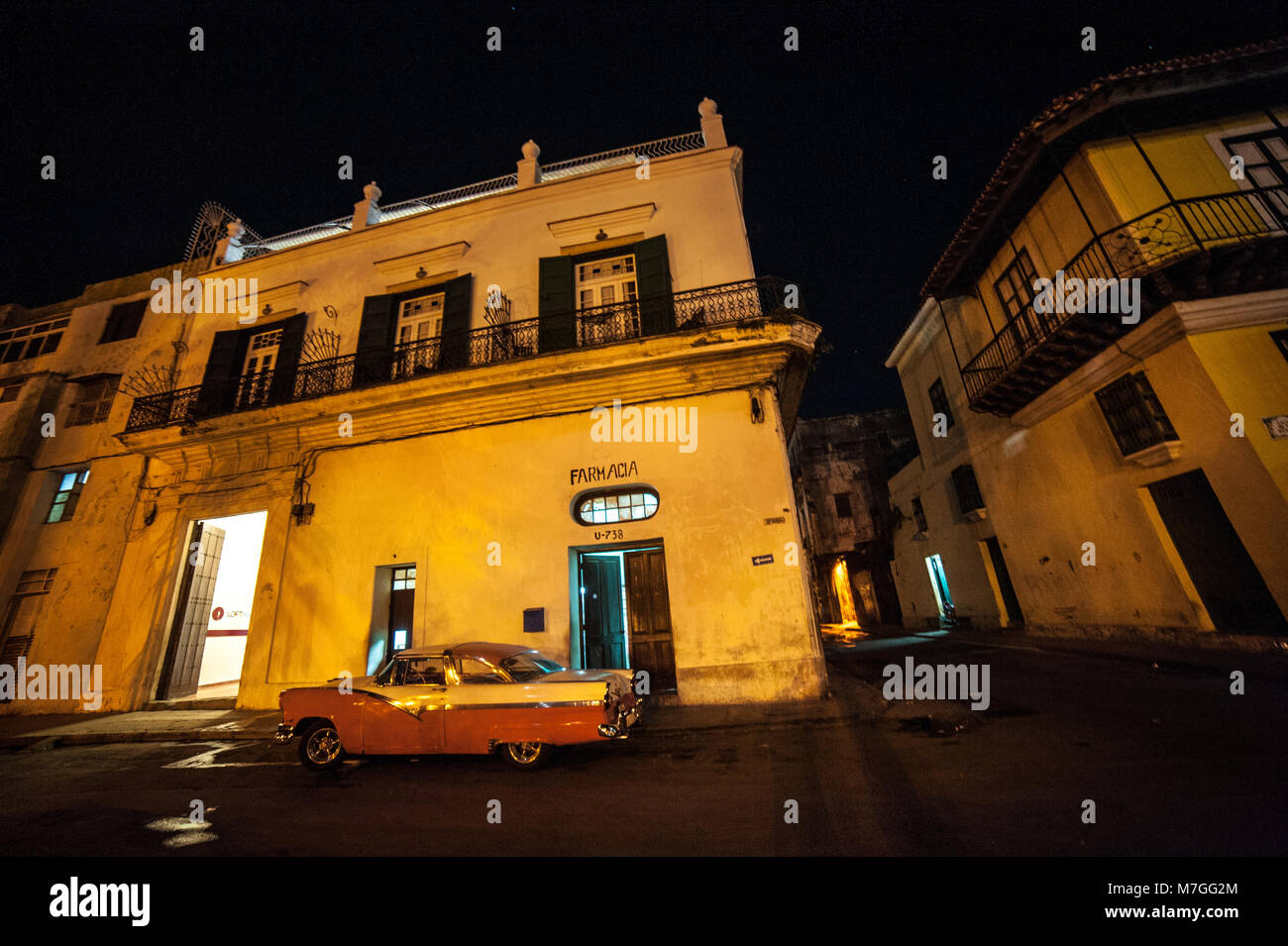 Un clásico americano coche aparcado fuera de una farmacia en La Habana, Cuba, en la noche Foto de stock