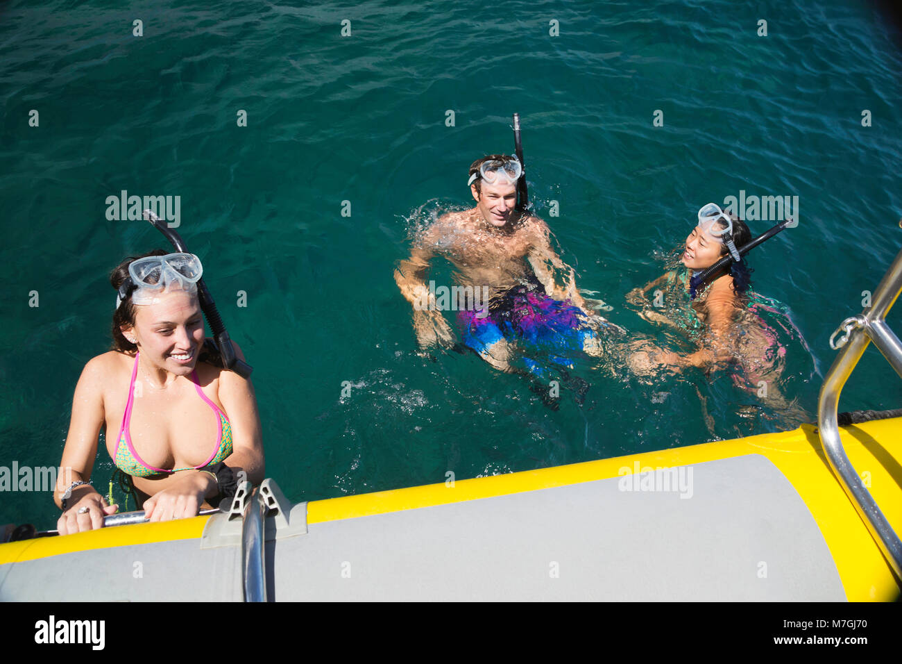Tres jóvenes snorklers (MR) buceo libre fuera de la isla de Lanai, regrese a su barco, Lanai, Hawaii. Foto de stock