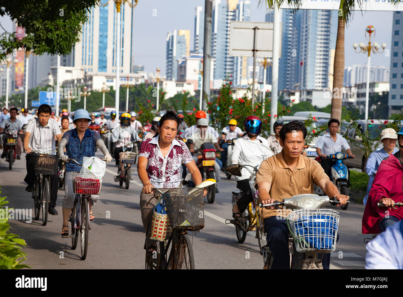 Gente que viaje, temprano en la mañana en bicicletas y scooters en un carril separado en la ciudad de Nanning, Guangxi, en el sur oeste de China. Foto de stock
