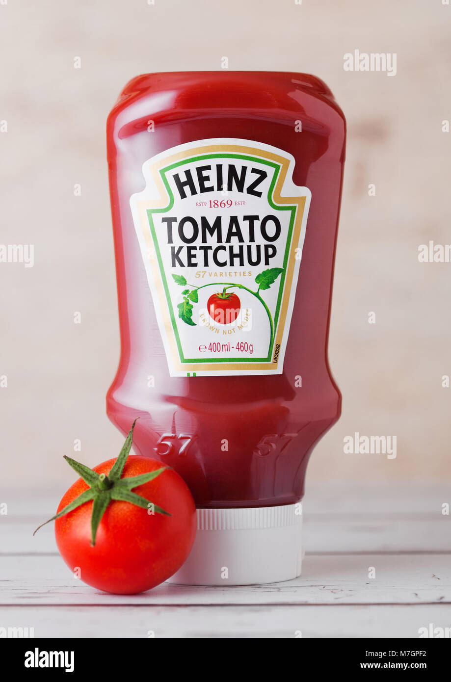 Londres, Reino Unido - 10 de marzo de 2018 : la botella de plástico de Ketchup Heinz sobre fondo de madera con tomate crudo. Fabricado por H.J. Heinz Company Foto de stock