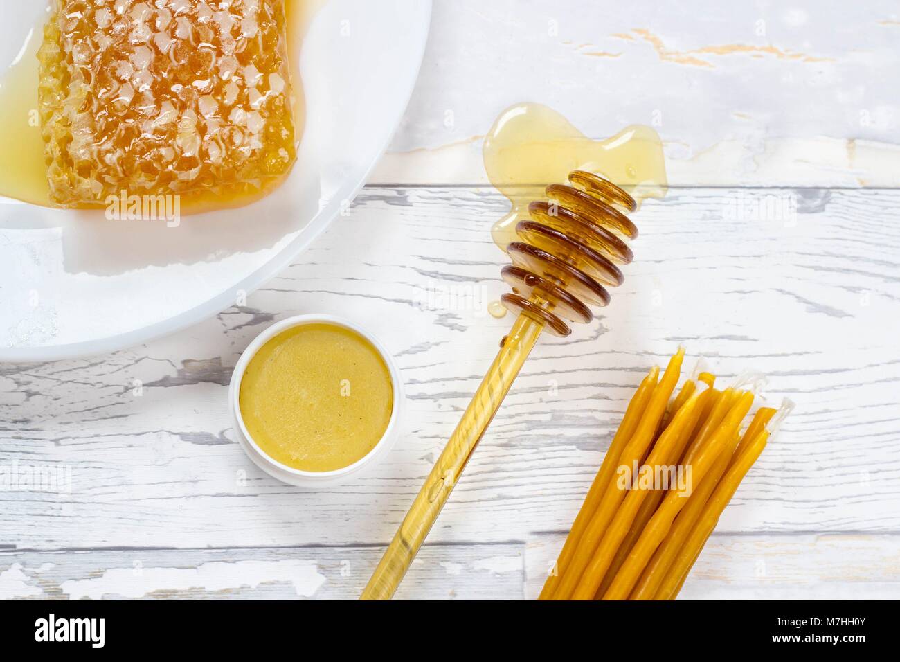 Panal de miel orgánica, bálsamo labial y velas de cera natural de madera sobre fondo blanco. Foto de stock