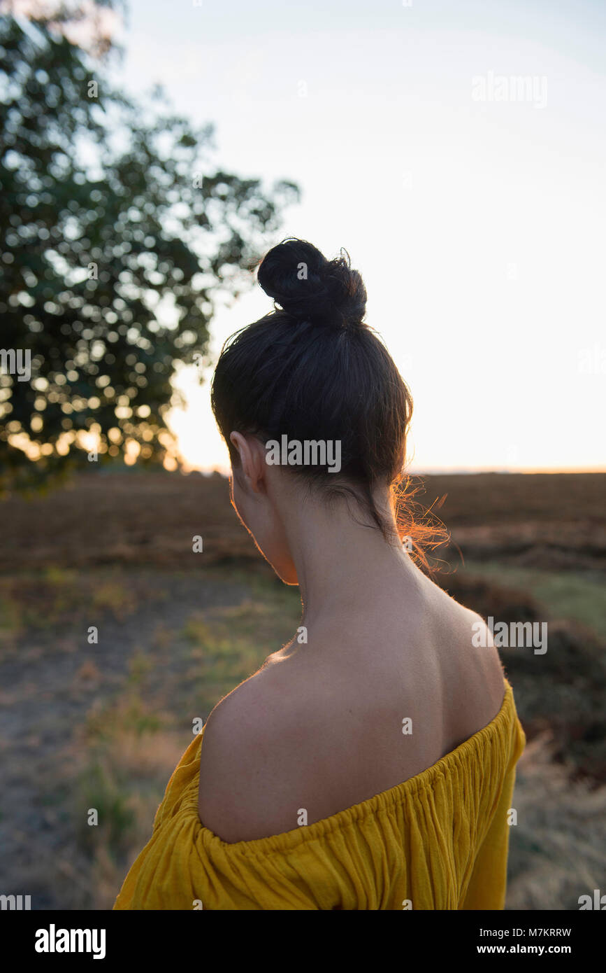 Una mujer de pie en un entorno rural, fotografiado por detrás. Foto de stock
