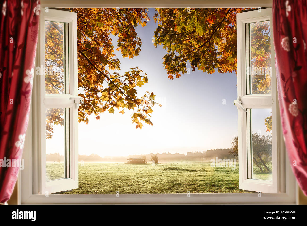 Ventana abierta con aire fresco y los paisajes rurales. Cortinas rojas muestran una ventana abierta en una casa moderna en una ubicación rural Foto de stock