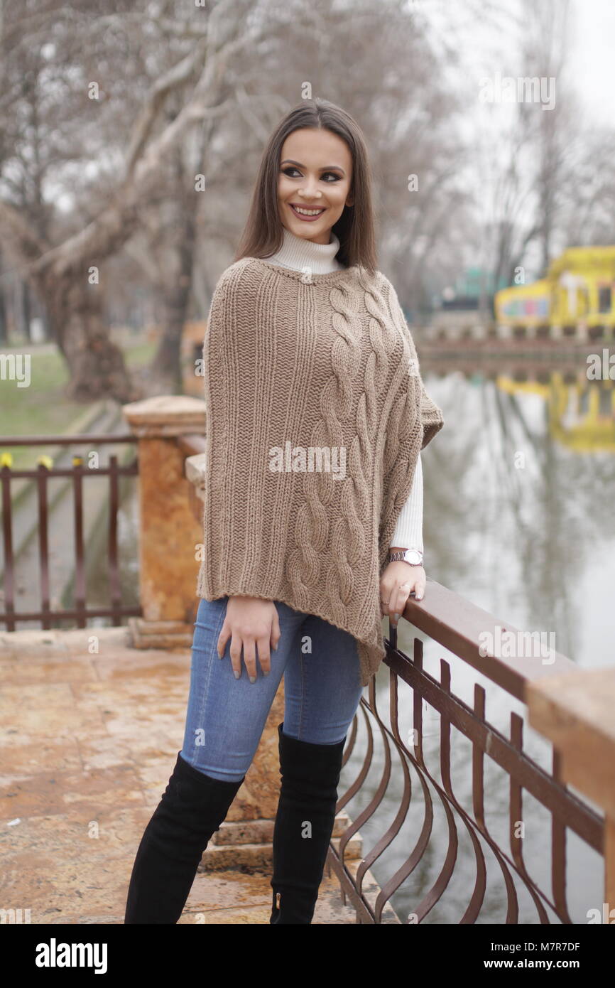 Muchacha con tejidos artesanales poncho marrón claro. Posición de pie en el  parque cerca del lago Fotografía de stock - Alamy