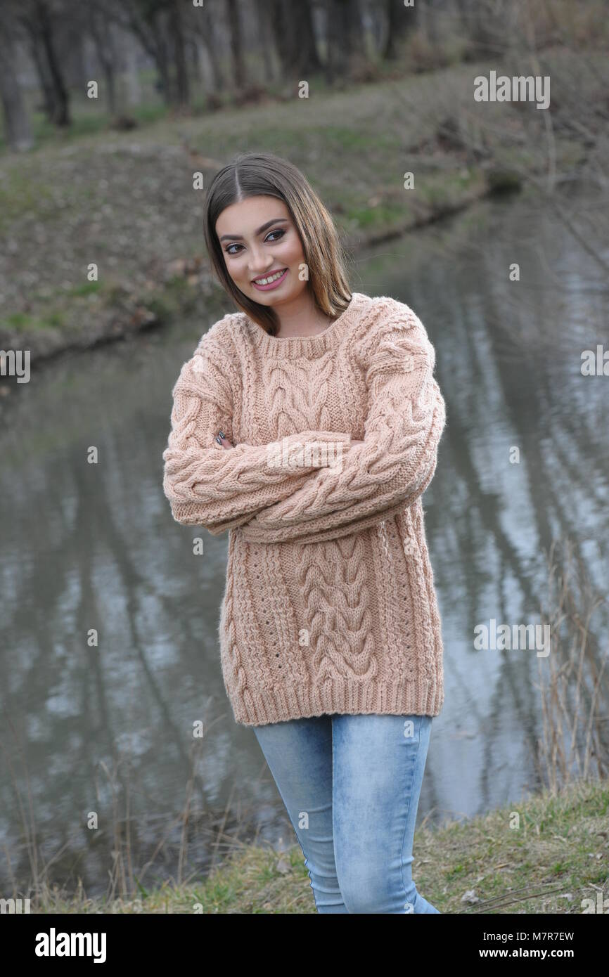 Niña en color marrón claro, tejidos artesanales sweater y jeans. Posición  de pie en el parque Fotografía de stock - Alamy