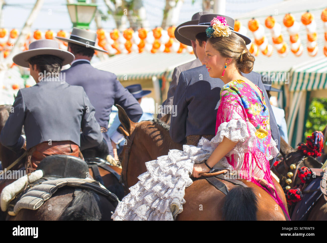 Gente vestida con trajes de flamenca tradicional en caballo en Sevilla Foto de stock