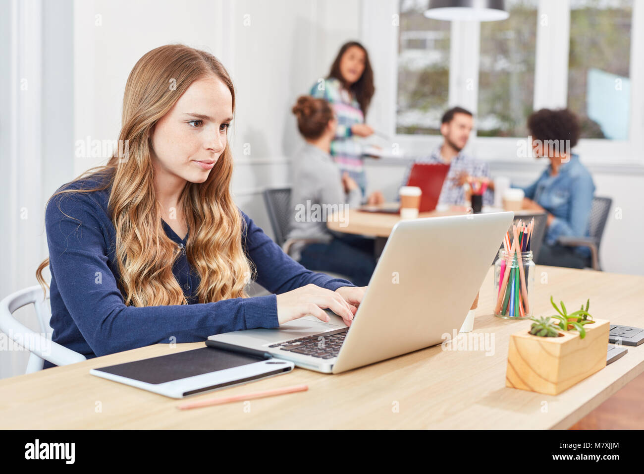 Empresa joven mujer concentratedly escribe en el ordenador portátil en la oficina coworking Foto de stock
