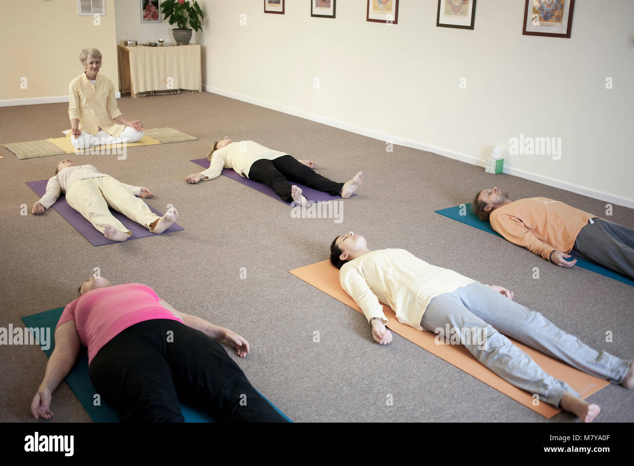 Los jóvenes practicando la relajación también llamado yoga nidra. Guiado  por un instructor sentando en shavasana sobre azul colchonetas para yoga en  el parquet en el interior Fotografía de stock - Alamy