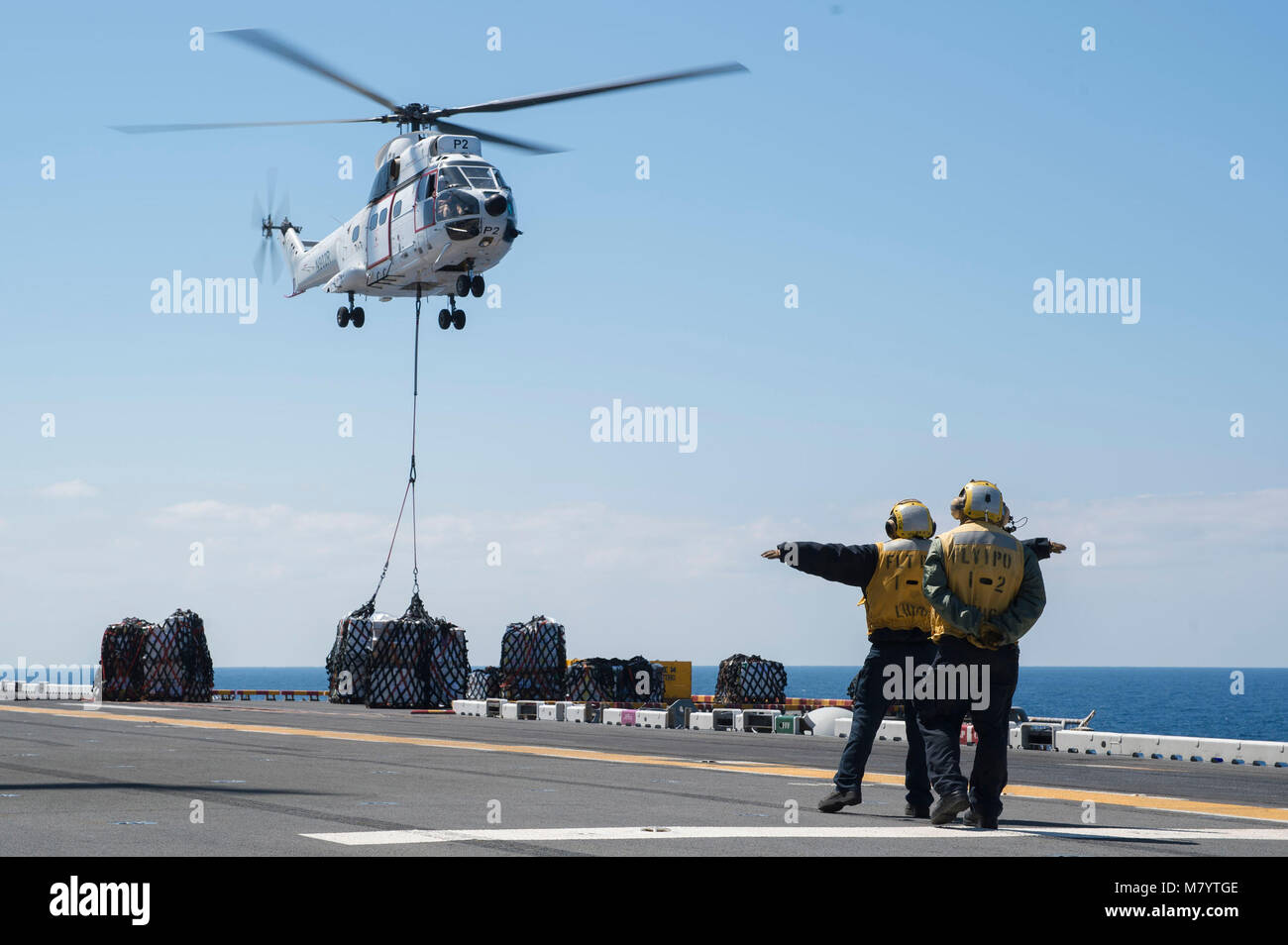180311-N-RD713-008 Mar de Filipinas (11 de marzo de 2018) Aviador Aprendiz Elizabeth Ramírez, de izquierda, de Reno, Nevada, y aviación Boatswain's Mate (manejo) de 2ª clase de Génesis de montaña, de San Diego, una directa como-322 Super Puma helicóptero, asignado a la carga seca y municiones buque USNS César Chávez (T-AKE 14), en la cubierta de vuelo del buque de asalto anfibio USS Bonhomme Richard (LHD 6) durante una reposición en alta mar. Bonhomme Richard está funcionando en la región del Indo-Pacífico como parte de una patrulla regularmente programada y proporciona una capacidad de respuesta rápida en caso de una contingencia o regionales Foto de stock