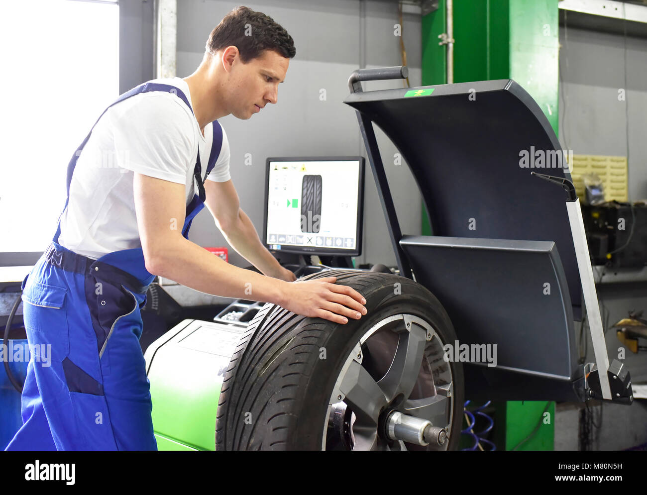 El cambio de neumáticos en un garaje - Ensamblador balancear un neumático  de la máquina Fotografía de stock - Alamy