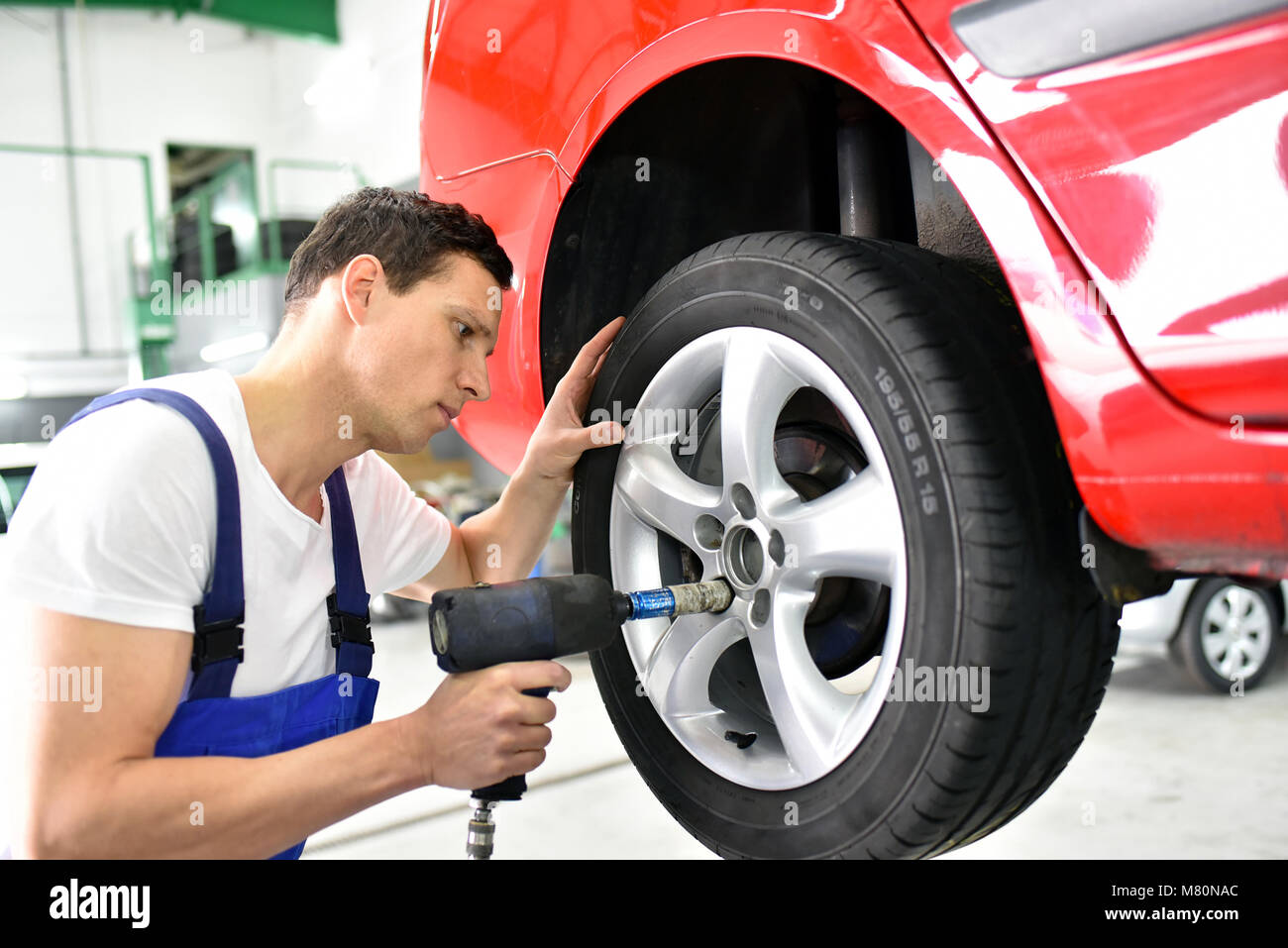 El cambio de neumáticos en un taller de reparación de automóviles -  trabajador reúne las llantas en el vehículo Fotografía de stock - Alamy