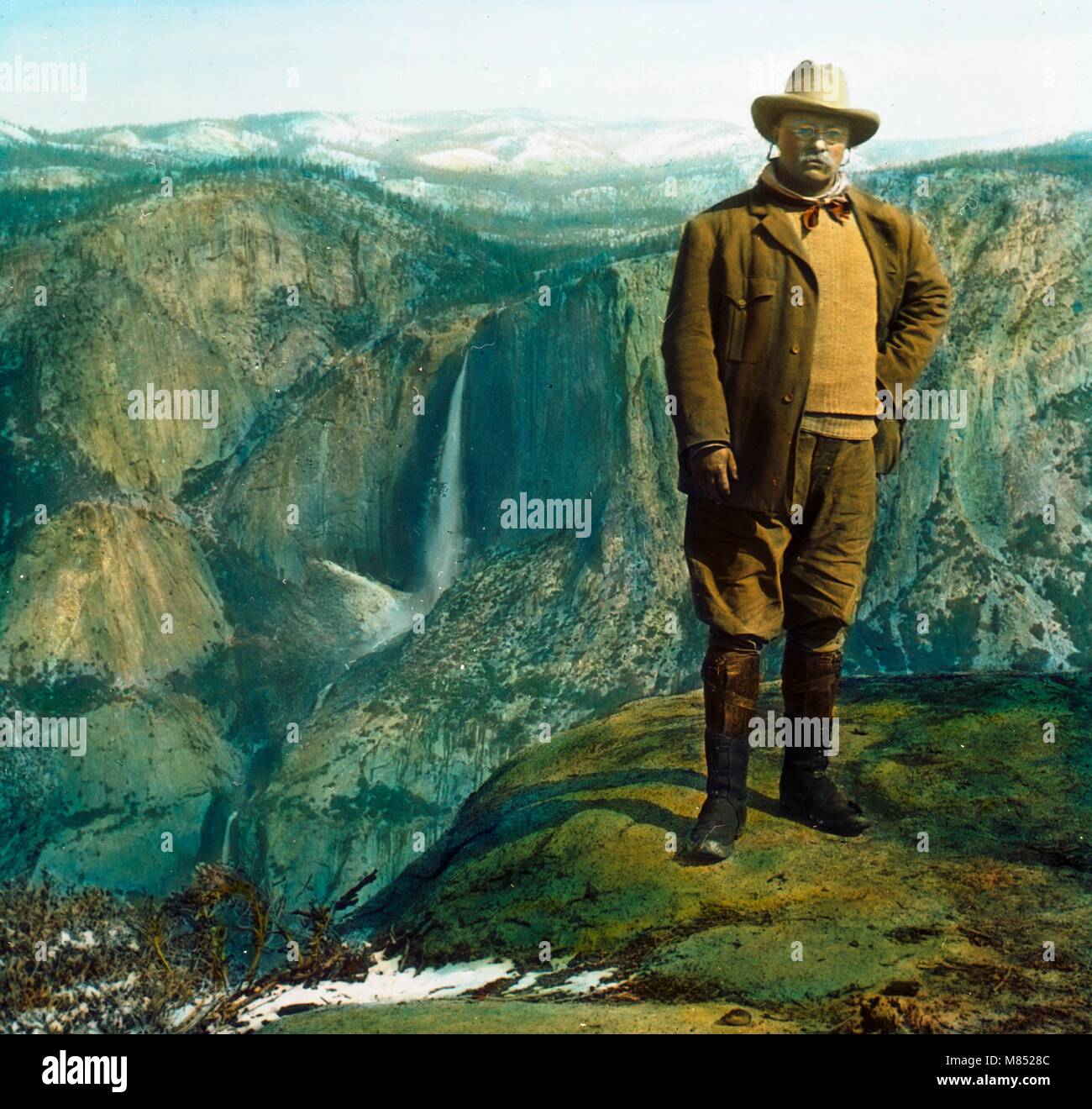 Retrato coloreado del presidente y conservacionista estadounidense Theodore  'Teddy' Roosevelt Jr (1858 - 1919) posando sobre la roca colgante en la  cima de Glacier Point con las cataratas Yosemite en el fondo,