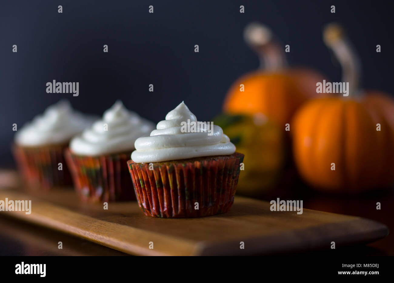 Pumpkin Spice deliciosos Cupcakes con glaseado de Queso Crema con calabazas en el fondo Foto de stock