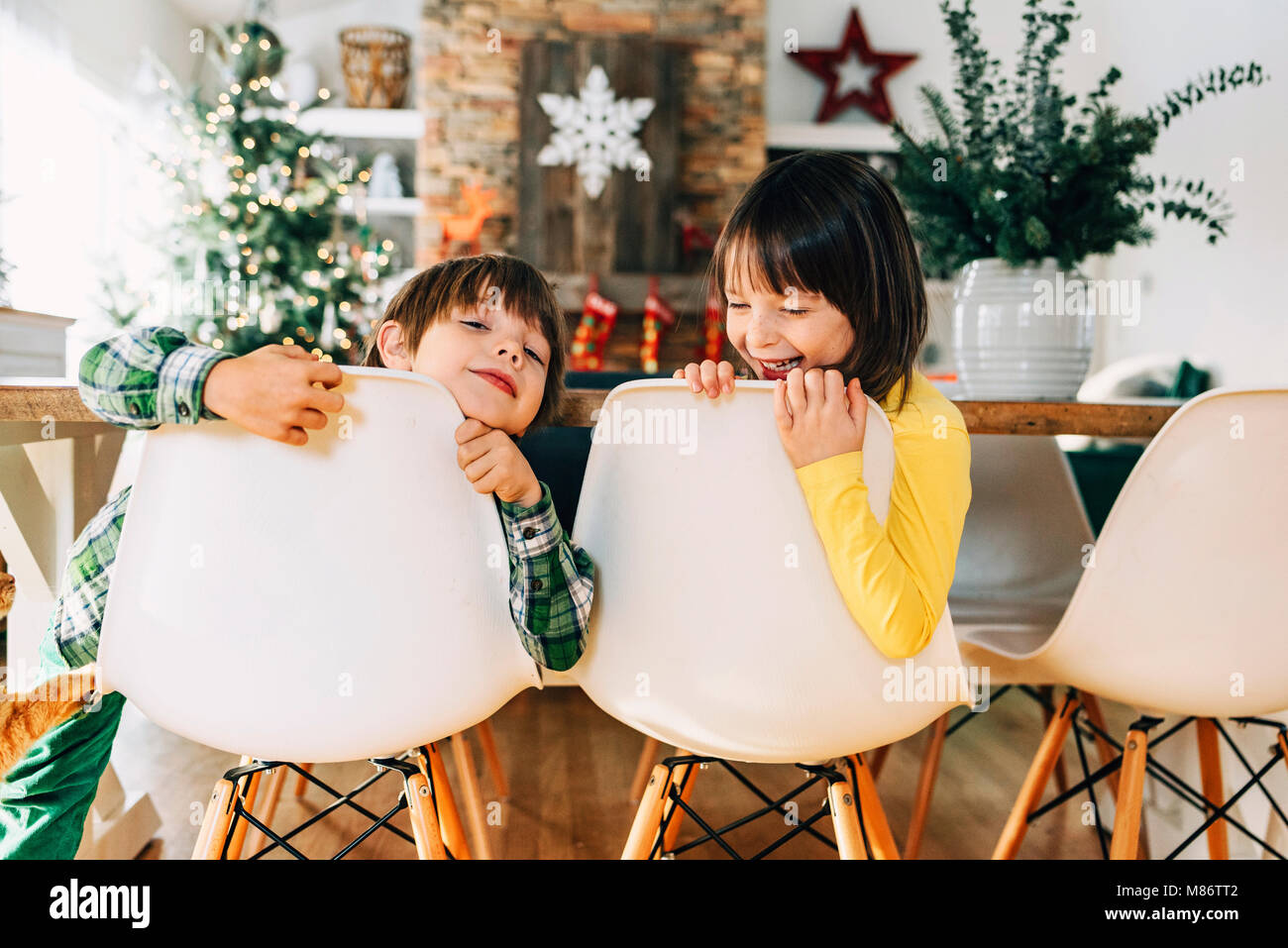 Chico y chica sentada en la mesa del comedor jugando en Navidad Foto de stock