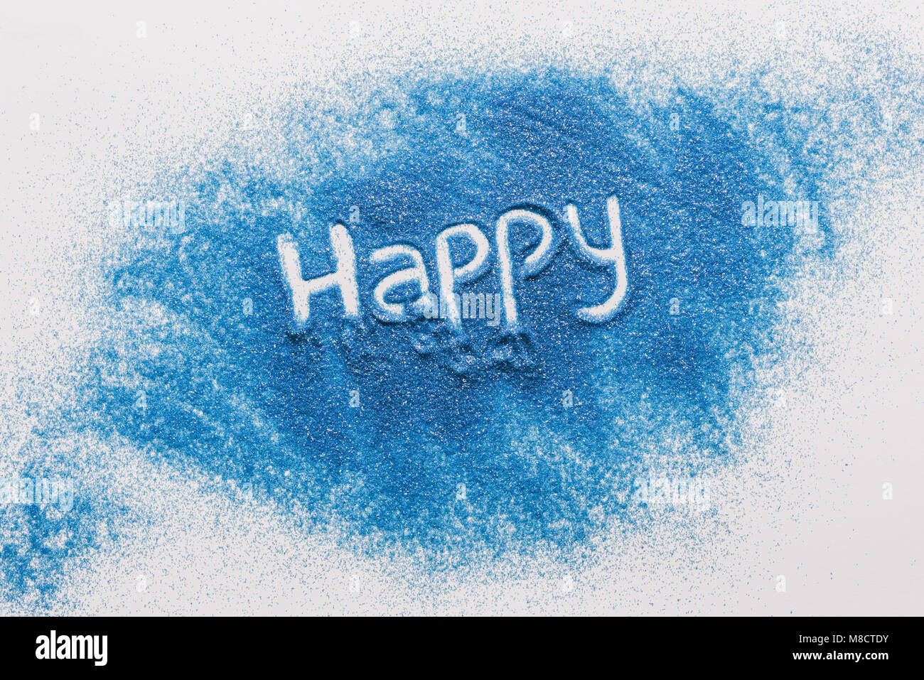 Vista superior del signo feliz hecha de arena azul en la superficie blanca Foto de stock