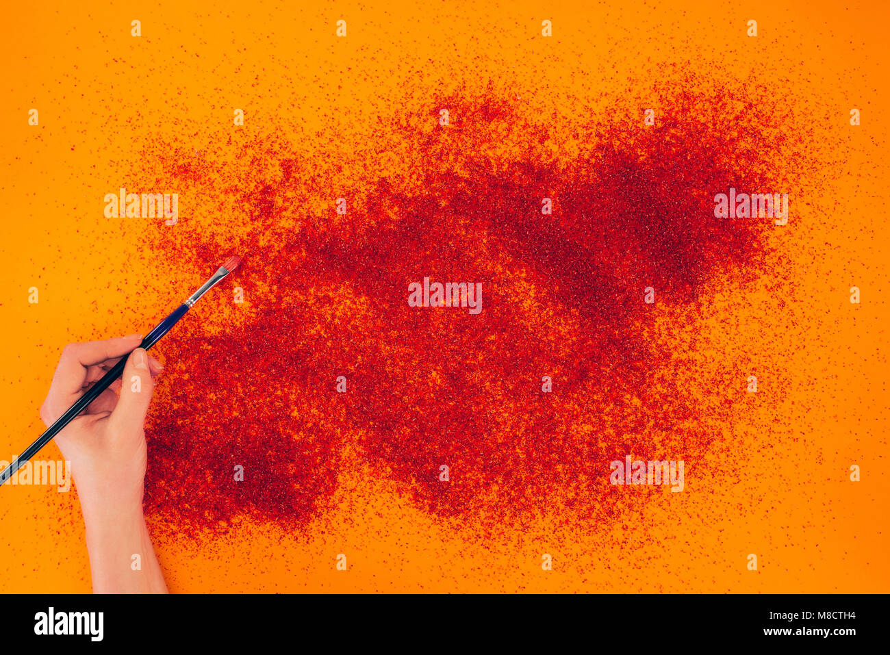 Imagen recortada de la mujer haciendo animación en arena naranja Foto de stock