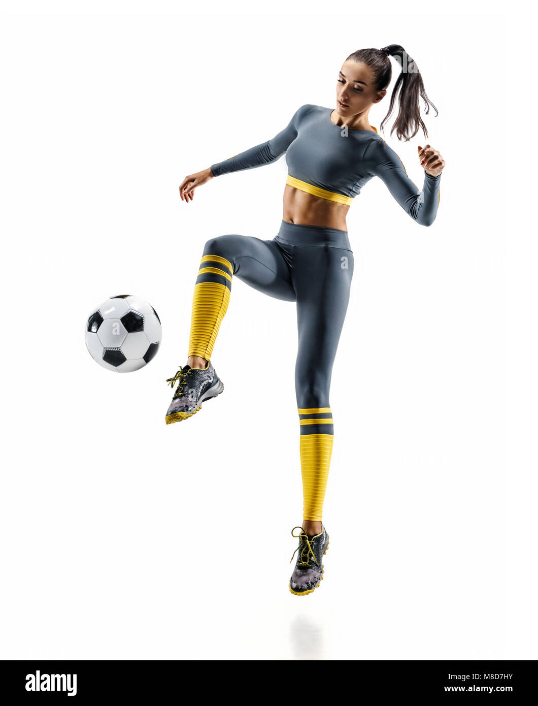 Jugador de fútbol en acción. Foto de mujer deportiva en ropa deportiva aislado fondo blanco. Movimiento dinámico. Foto de stock