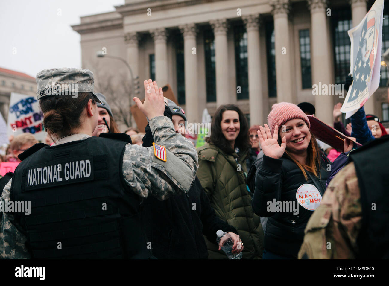 Los manifestantes alta cinco mujeres miembros de la Guardia Nacional mientras están marchando en la sección de Mujeres de la marcha en Washington D.C., 21 de enero de 2017 Foto de stock