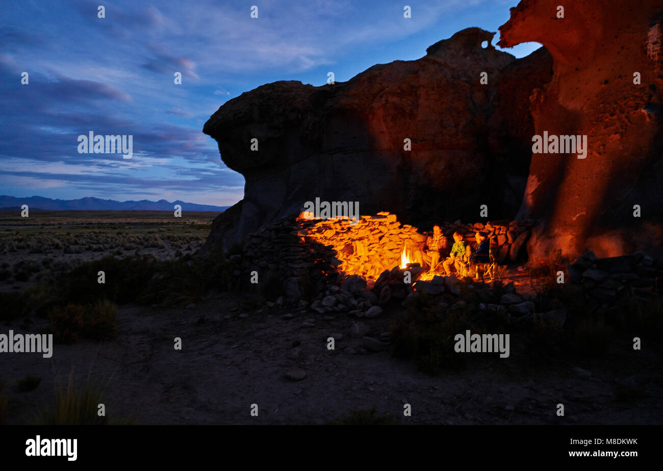 Madre e hijos, sentado junto al fuego de campamento al anochecer, Oruro, Oruro, Bolivia, América del Sur Foto de stock
