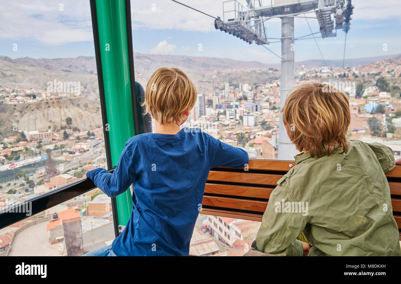 Dos chicos en teleférico, mirando nuestra de cristal a vista, vista trasera, La Paz, Bolivia, América del Sur Foto de stock