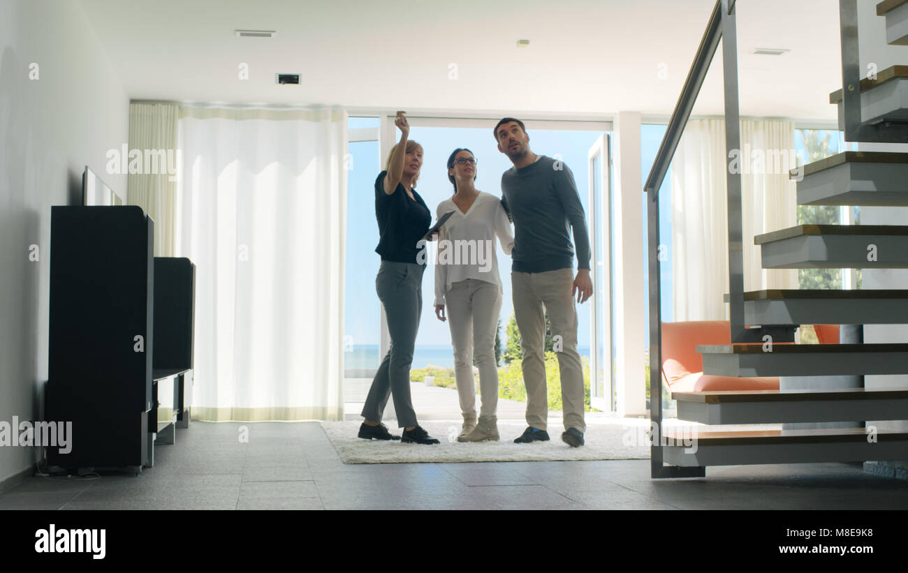 Agencia Inmobiliaria profesional muestra Elegante Casa moderna a una hermosa pareja de jóvenes que están en el mercado de compras/ alquilar casa nueva. Foto de stock