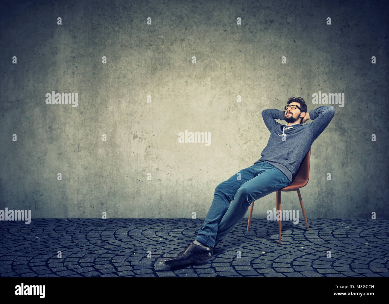 Hombre en ropa informal sentado en una silla y soñar despierto Foto de stock