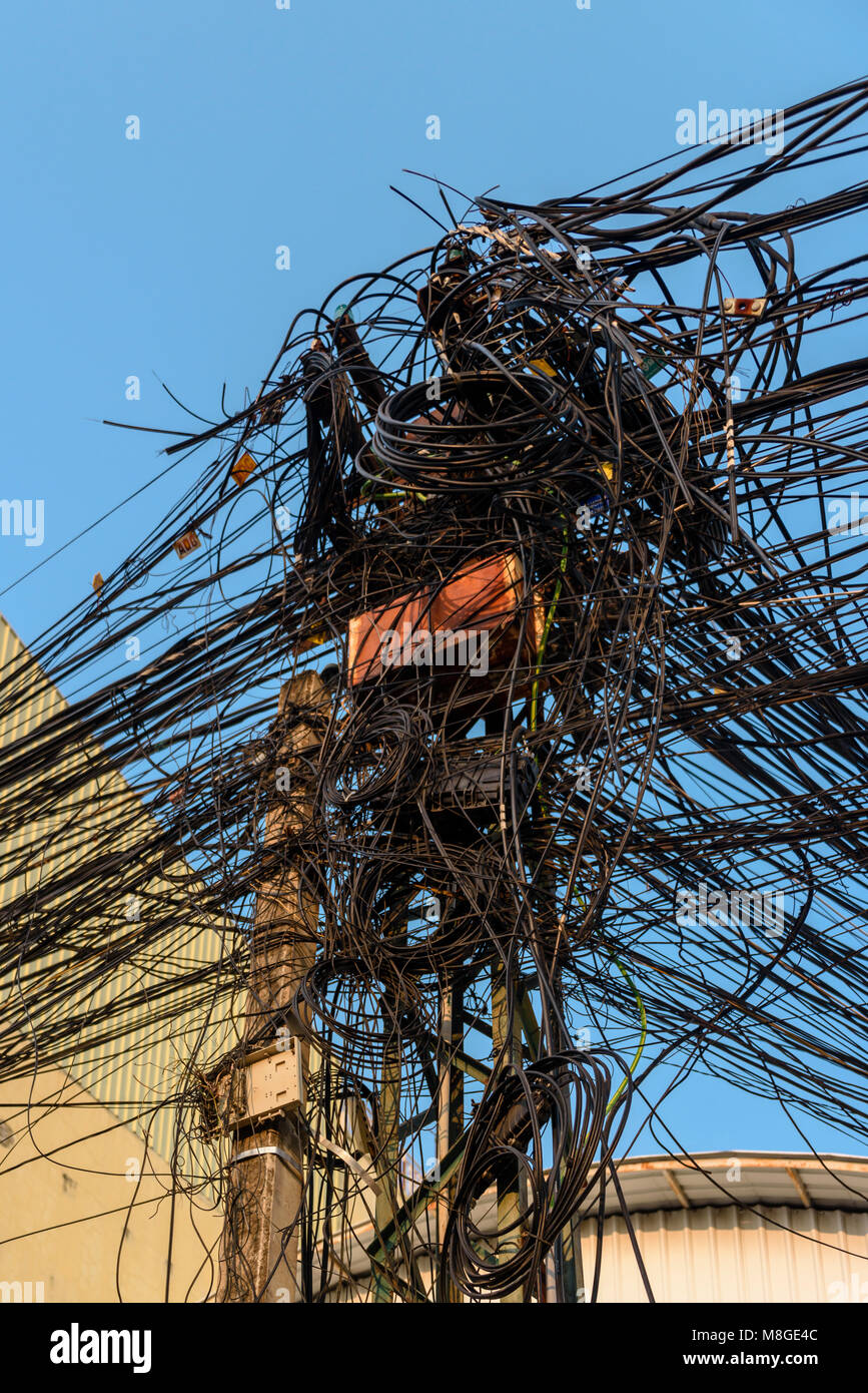 Poste de electricidad con docenas de peligrosos desordenado marañas de cables y alambres Foto de stock