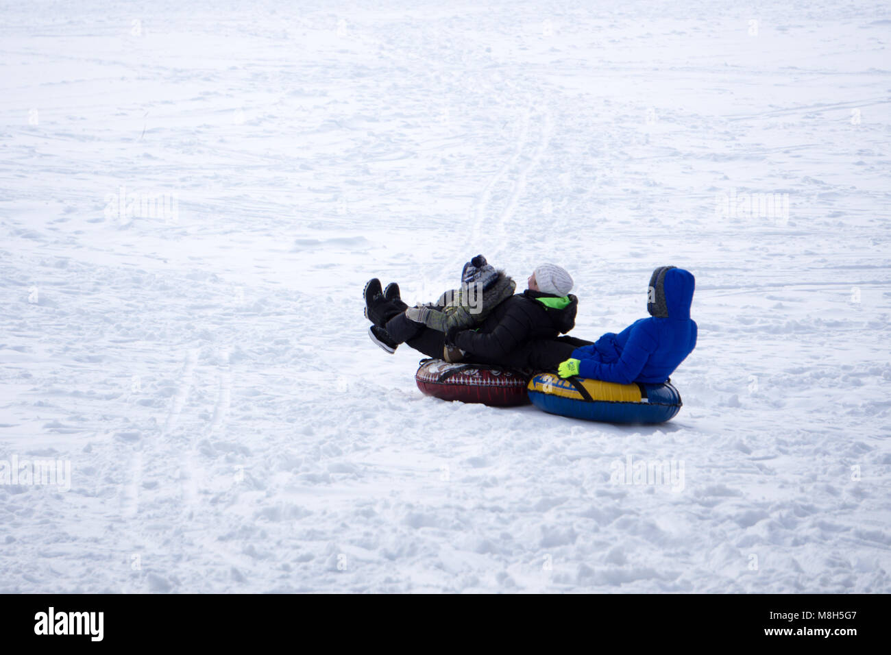 Padre e hijo de trineo durante las vacaciones de invierno. Feliz papá y  Little Boy jugando con trineo para nieve. Hombre con niño sonriente sentado  en bobsledge en el sno Fotografía de