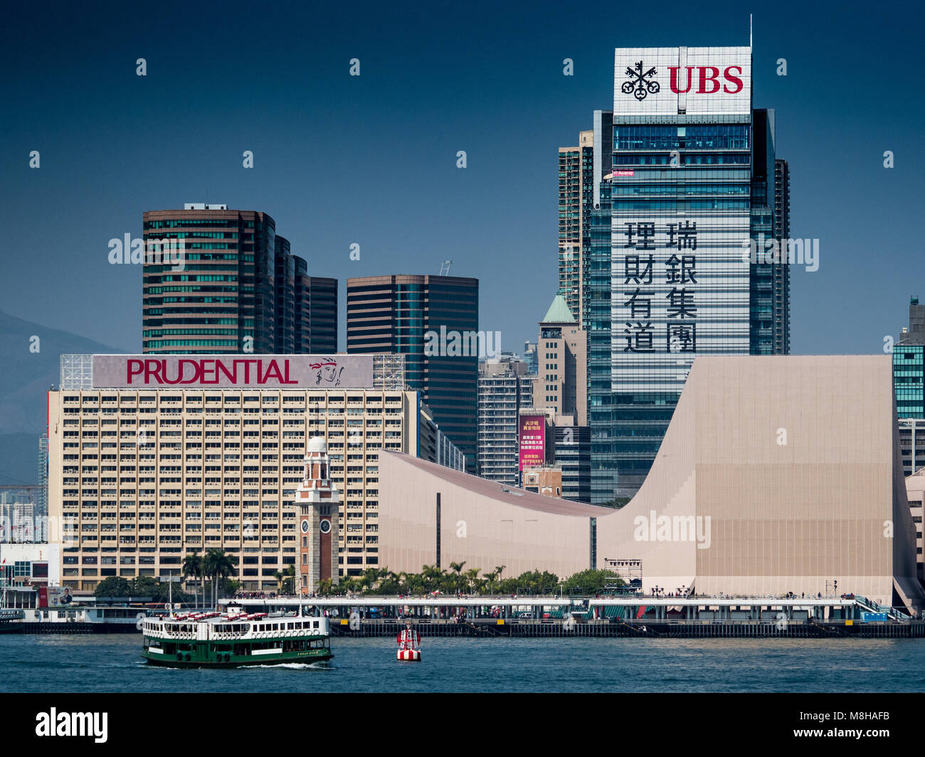 Hong Kong - Star Ferry velas delante de UBS y grandes anuncios prudenciales en el lado de Kowloon de Victoria harbour Foto de stock