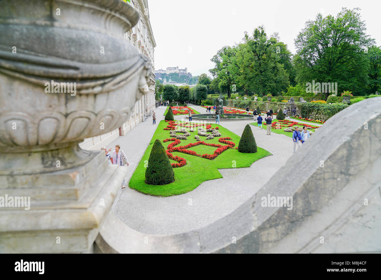 Salzburgo Austria   6 de septiembre de 2017; los turistas disfrutan de caminar por los hermosos jardines de Mirabell viewd del pasadizo elevado con el edificio del palacio de LEF. Foto de stock