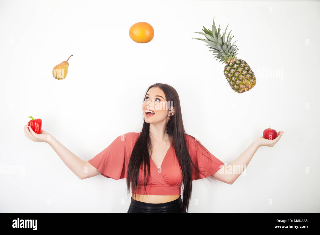 Una bonita adolescente malabarismos con sus cinco al día de frutas y verduras Foto de stock