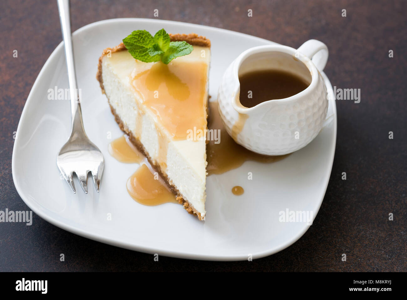 Cheesecake con salsa de caramelo sobre placa blanca, acercamiento, el enfoque selectivo. Trozo de tarta de queso, tarta de caramelo Foto de stock