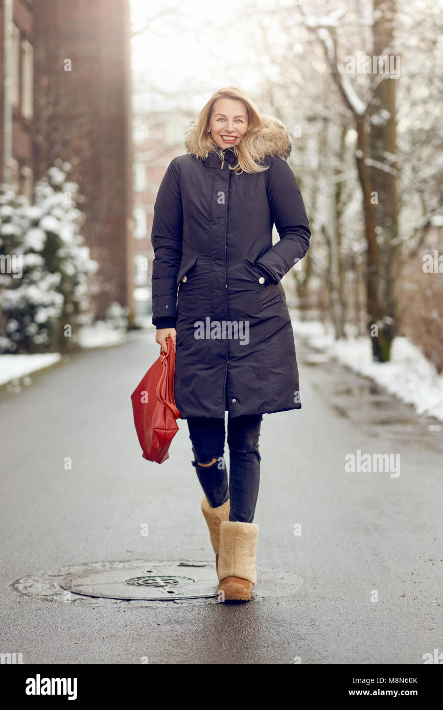 Atractiva joven moda mujer rubia en un cálido abrigo y botas furry