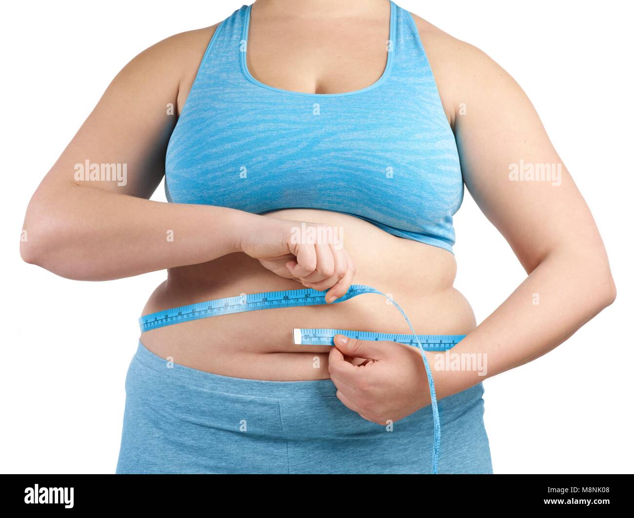 Mujer con sobrepeso midiendo su cintura con una cinta métrica. Foto de stock