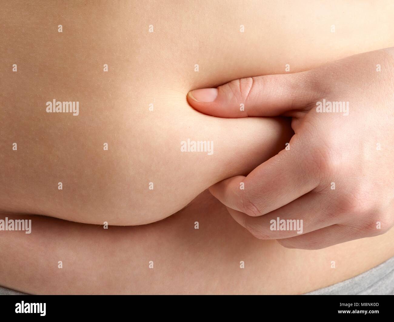 Sobrepeso mujer sosteniendo la grasa alrededor de su cintura. Foto de stock