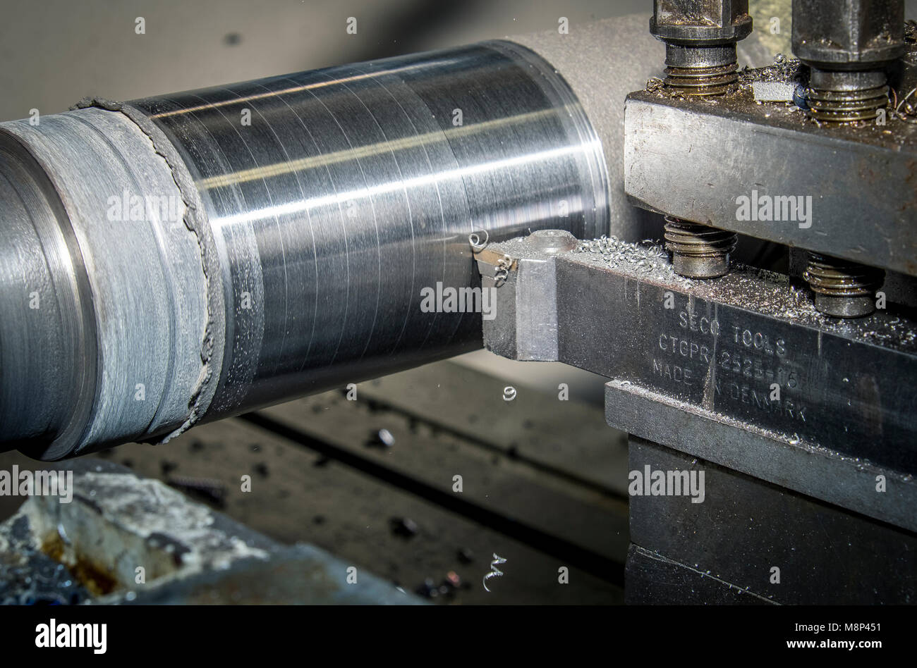 Un eje de acero está girado o corte en un cabrestante torno en un taller de  maquinaria para hacer que el diámetro de la barra de metal en el tamaño  correcto para