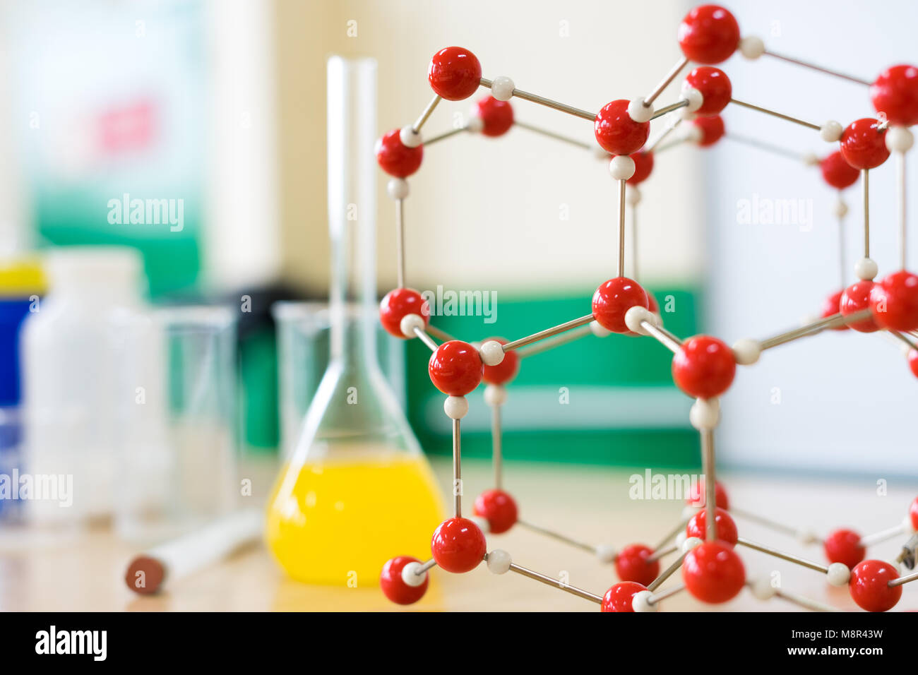 Cristalería con fórmula líquida química y modelo de estructura molecular en el laboratorio de ciencia en el aula desk. Foto de stock