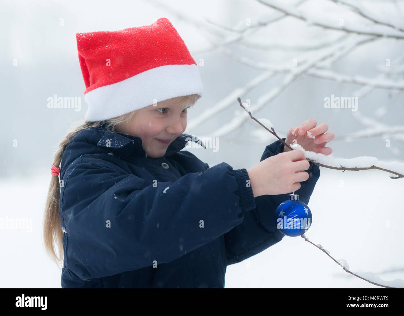 Ein Madchen Mit Weihnachtsmutze Und Kugel Im Schnee Fotografia De Stock Alamy