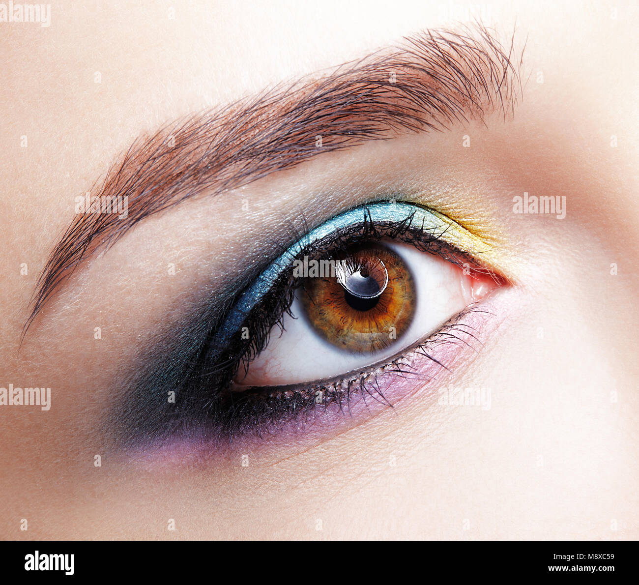 Closeup macro foto de mujer humana ojo. Mujer con natural noche vogue belleza facial maquillaje. Chica con una piel perfecta y lila - azul - amarillo ojos sh Foto de stock