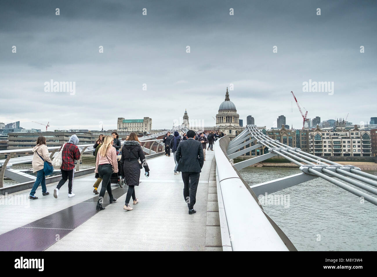Los peatones cruzando el Puente del Milenio en Londres en un frío día nublado. Foto de stock