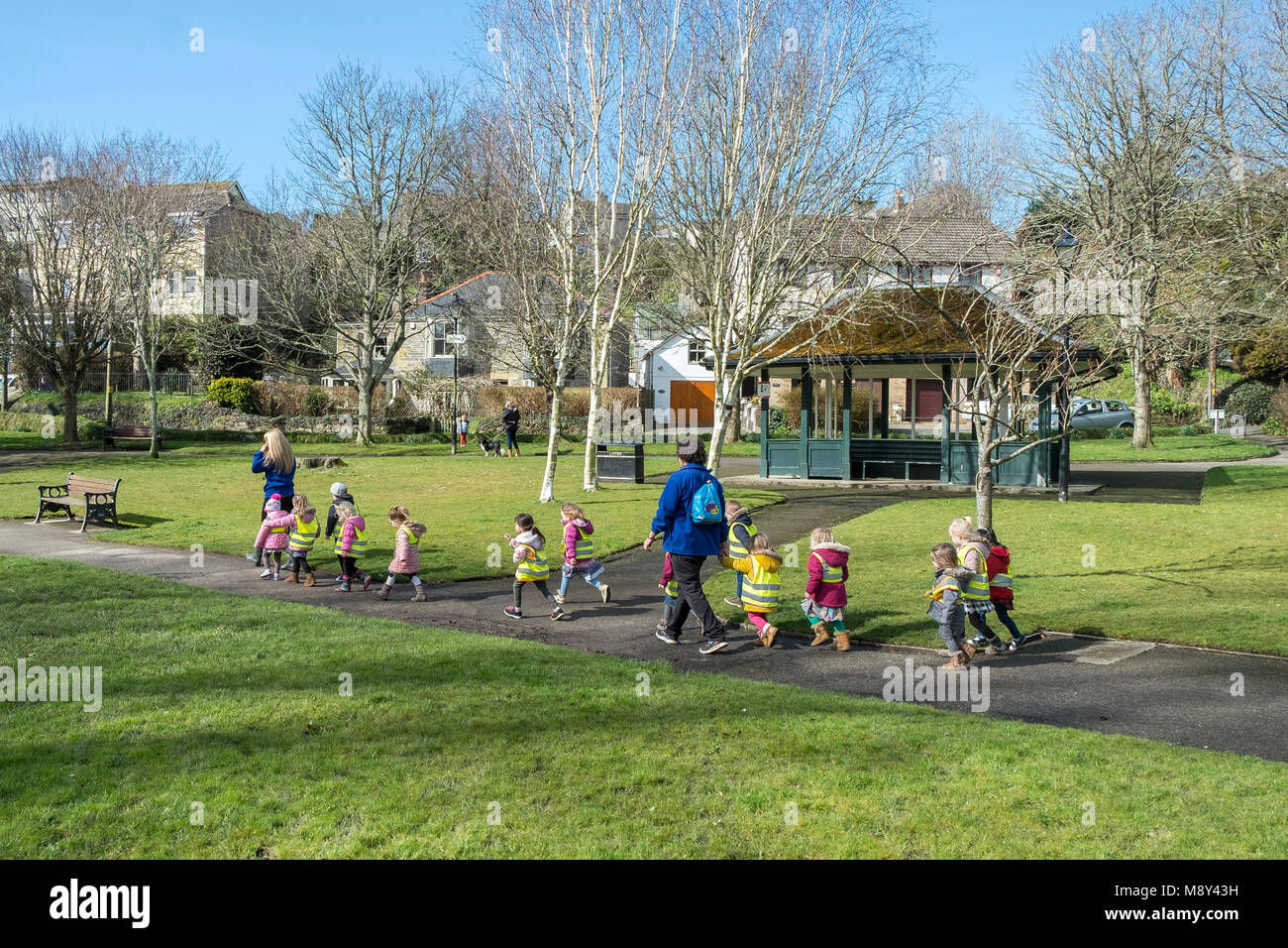 Los niños de una guardería y sus profesores caminando por los jardines Trenance en Newquay, Cornwall. Foto de stock