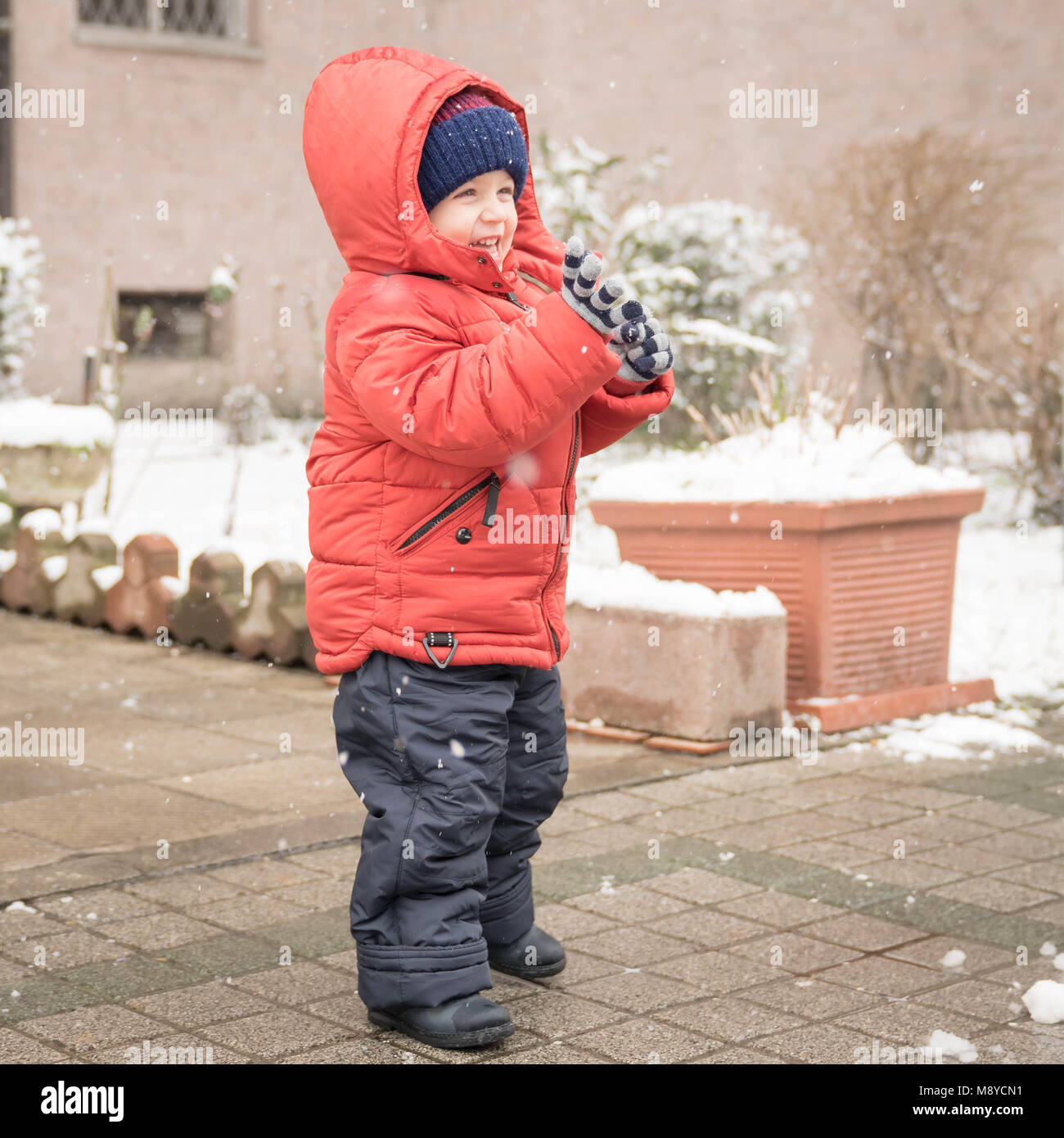 Niño niño niño con orejeras, guantes de nieve jugando alegremente en la  nieve