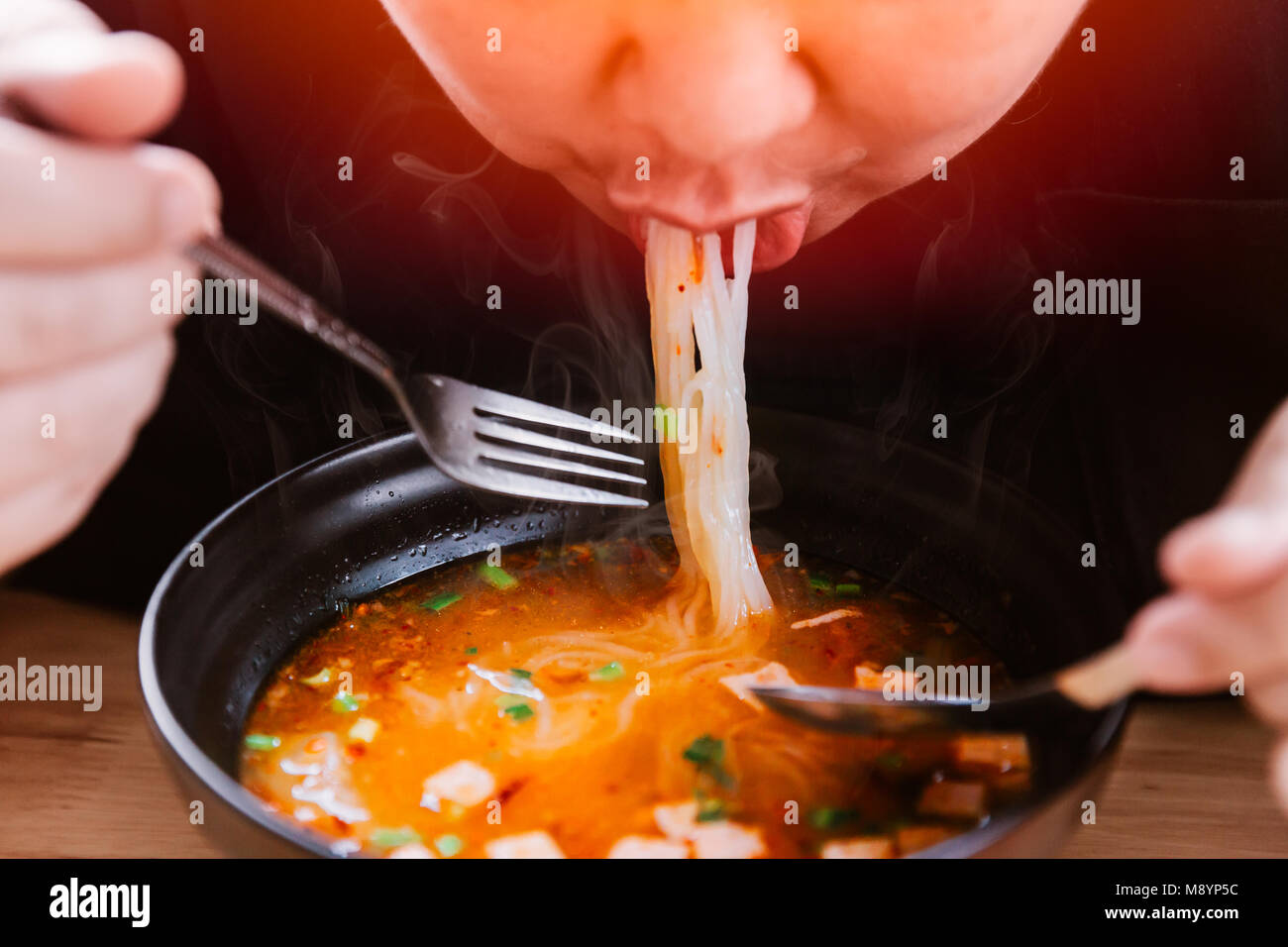 Hombre comiendo fideos picantes muy caliente y sabrosa comida deliciosa Foto de stock