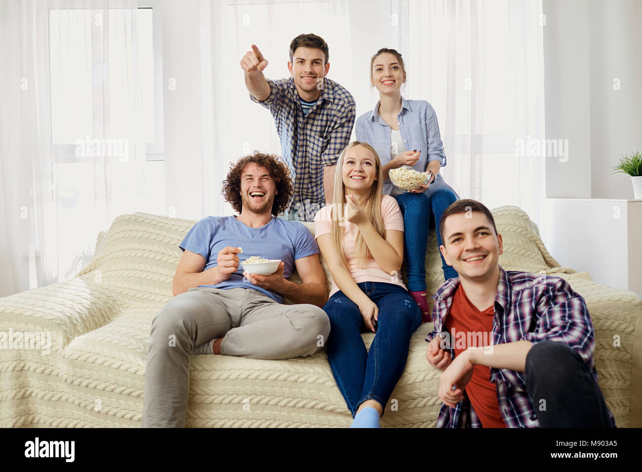 Un grupo de amigos, viendo la televisión en la habitación. Foto de stock