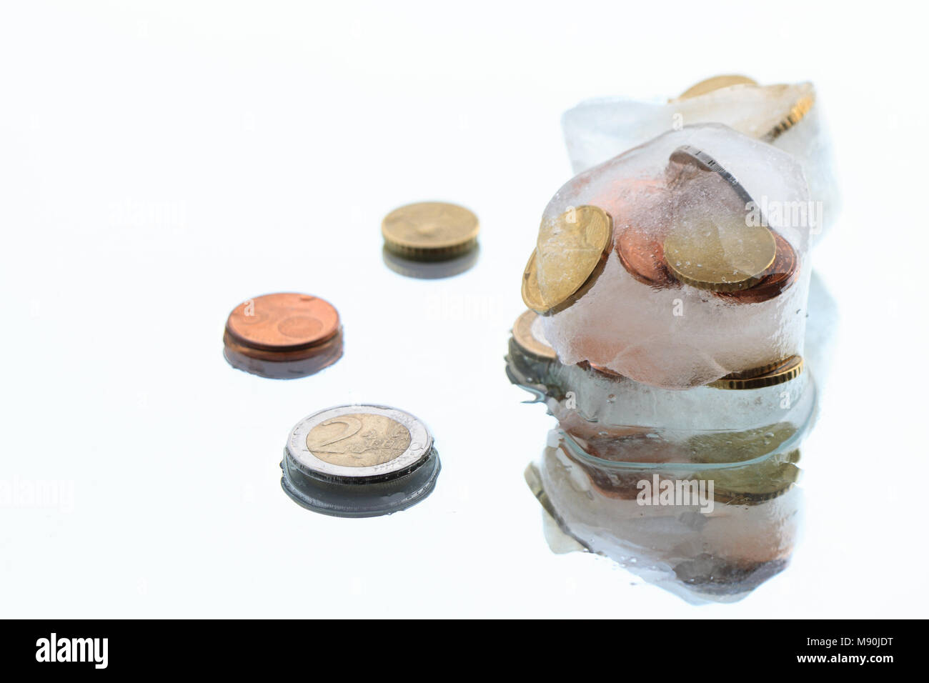 Monedas dentro de cubitos de hielo aislado sobre fondo blanco. Foto de stock
