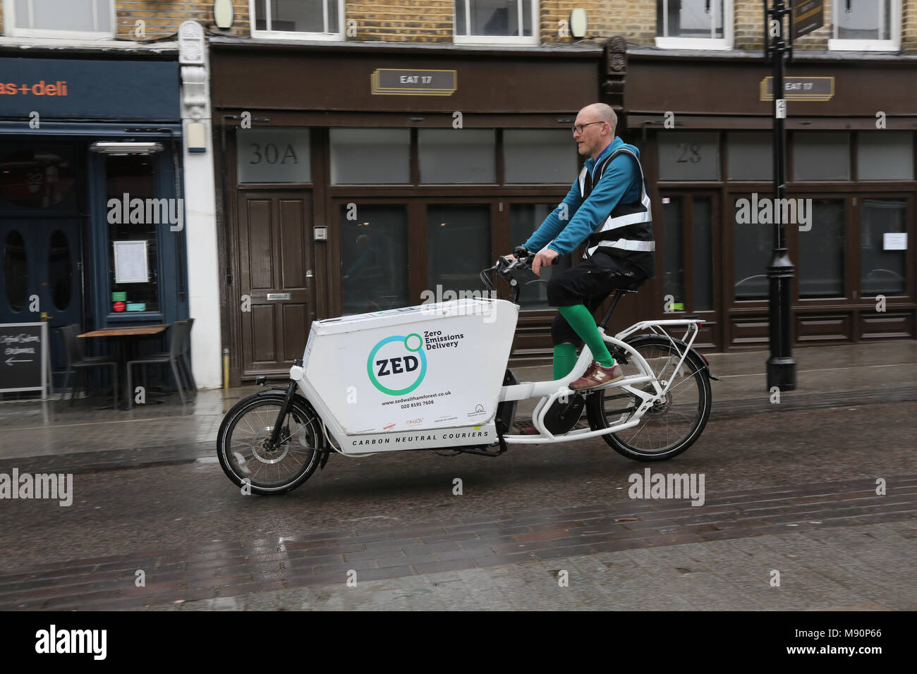 Un corredor de una empresa de distribución de emisiones cero utiliza una bicicleta de carga para distribuir mercancías en Walthamstow, en el norte de Londres. Foto de stock