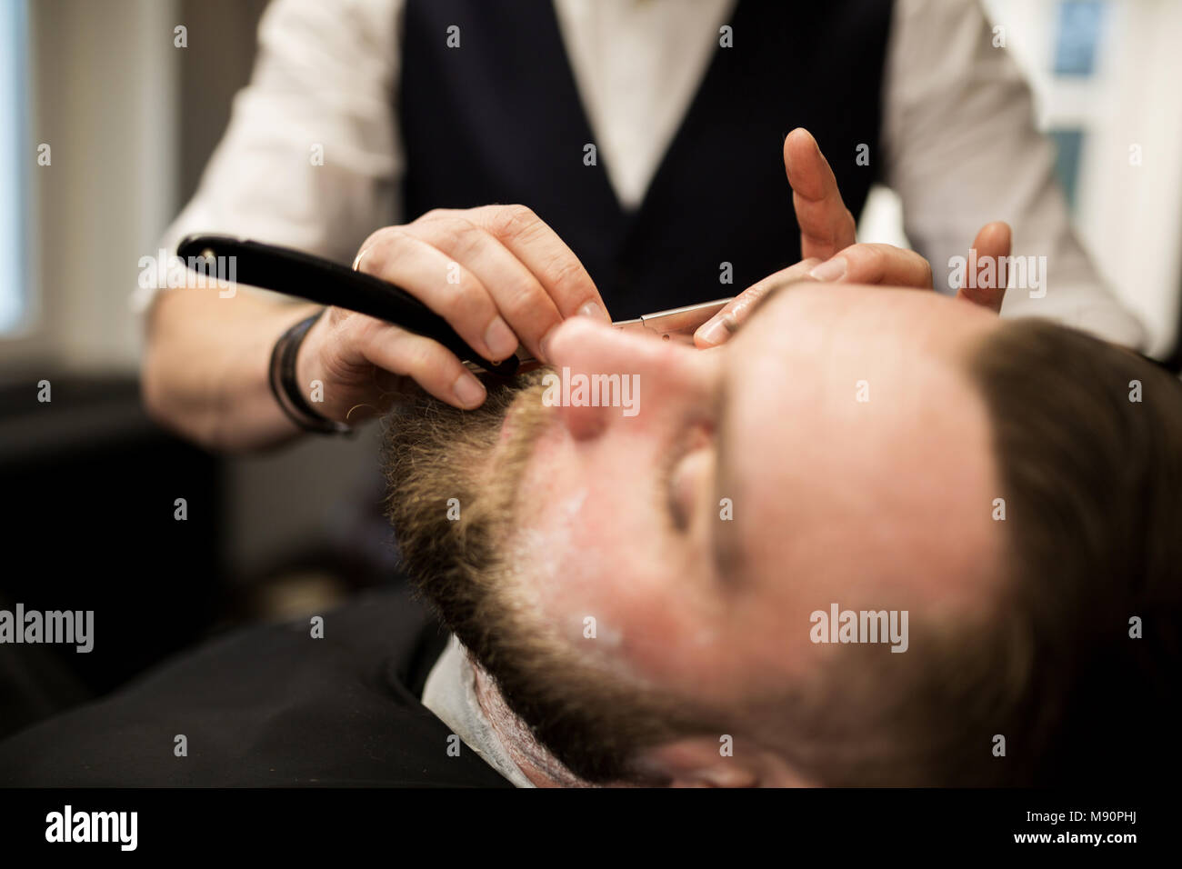 Retrato del hombre barbado siendo afeitado por el barbero Foto de stock