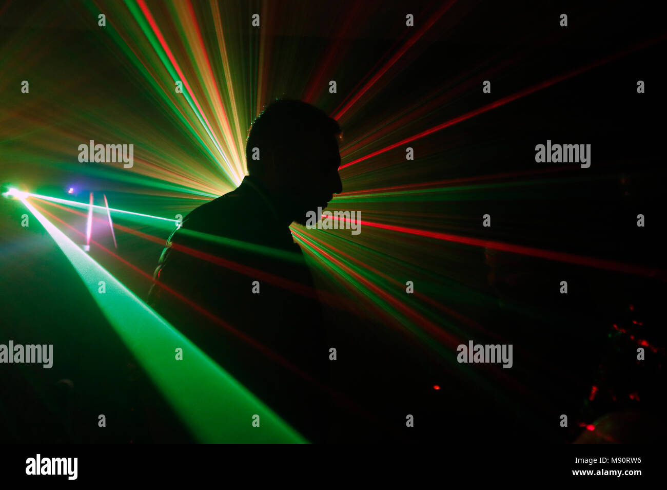 Silueta de un hombre a bailar a una discoteca con luces láser. Foto de stock