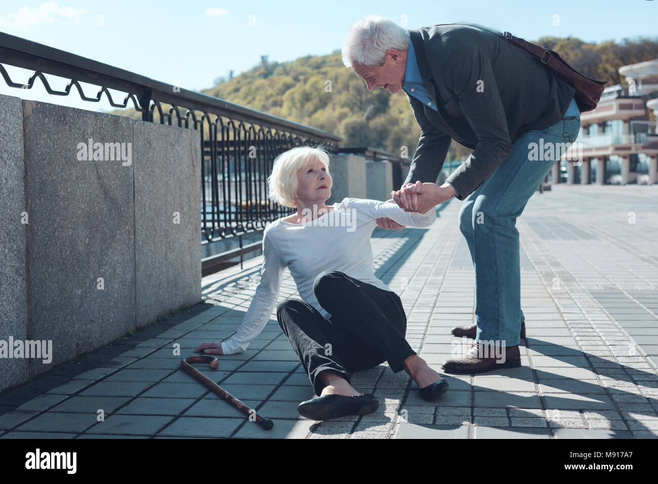 Consciente el hombre ayuda a ancianos extraña a levantarse Foto de stock