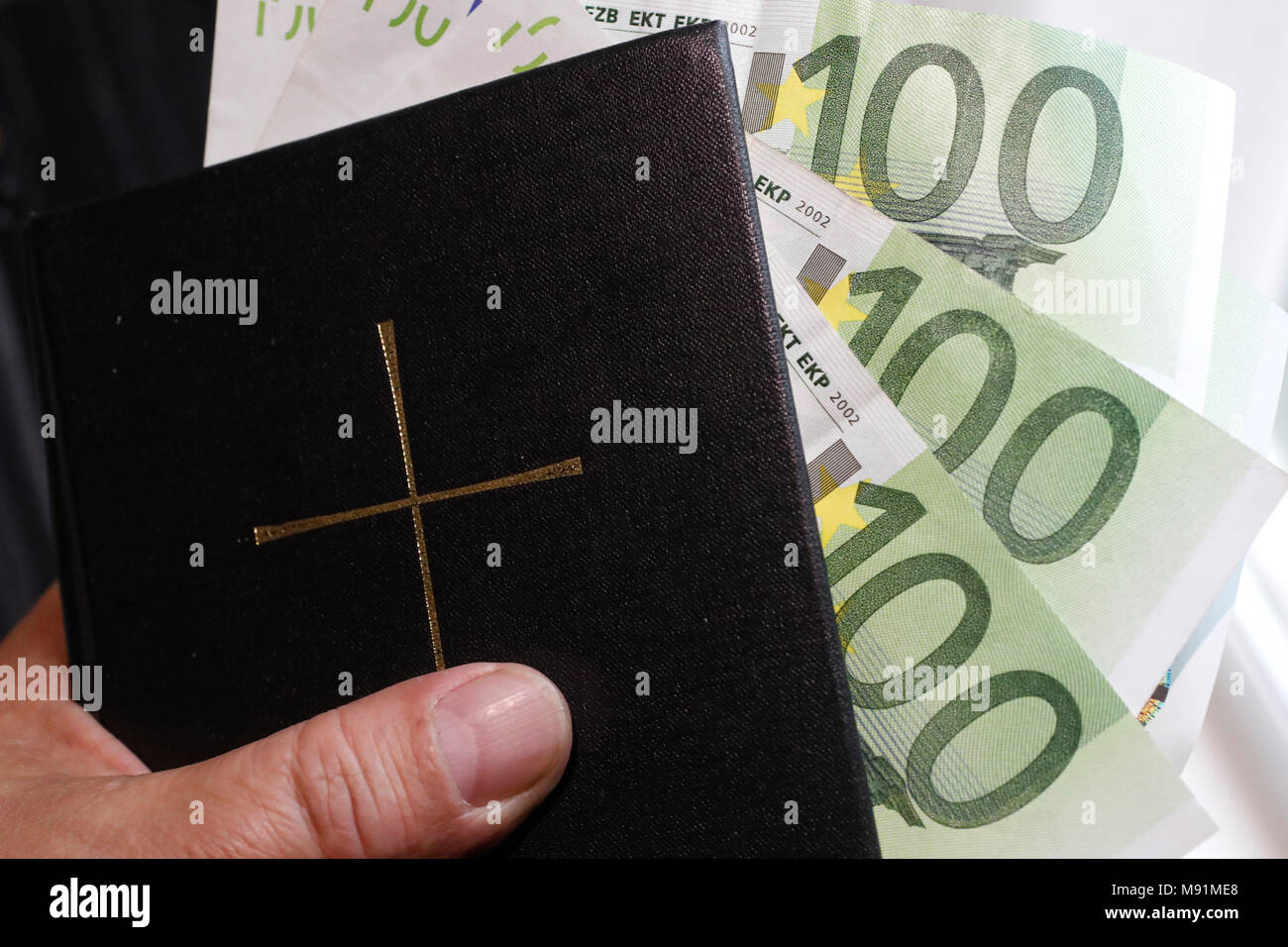 El dinero y la religión. La Santa Biblia y euros. Foto de stock